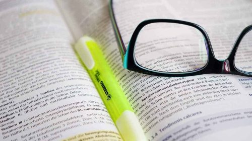 Glasses and a highlighter marker over a book